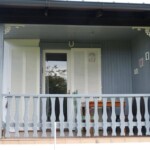 In den Ecken der Veranda geschnitzte Zierelemente aus Holz eingefügt. Die Eingangstüre samt Läden geschliffen und neu weiß.