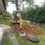 Kanalanschluss an unser Privathaus. Hier findet der erste "Spatenstich" statt. Von da an wurde über 100 Meter durch den Garten gegraben.